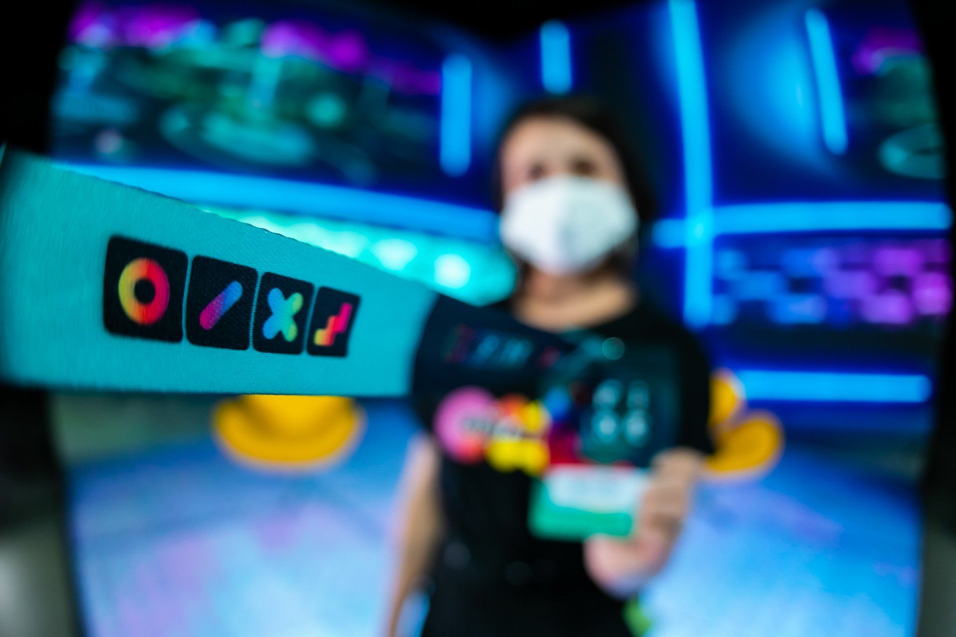 Uma mulher usando uma máscara está segurando uma placa que diz oxo