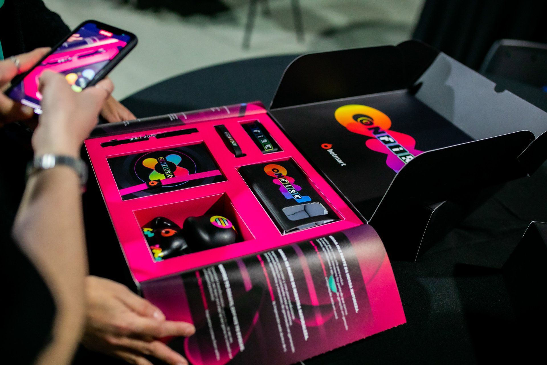 Uma pessoa está segurando um celular ao lado de uma caixa rosa