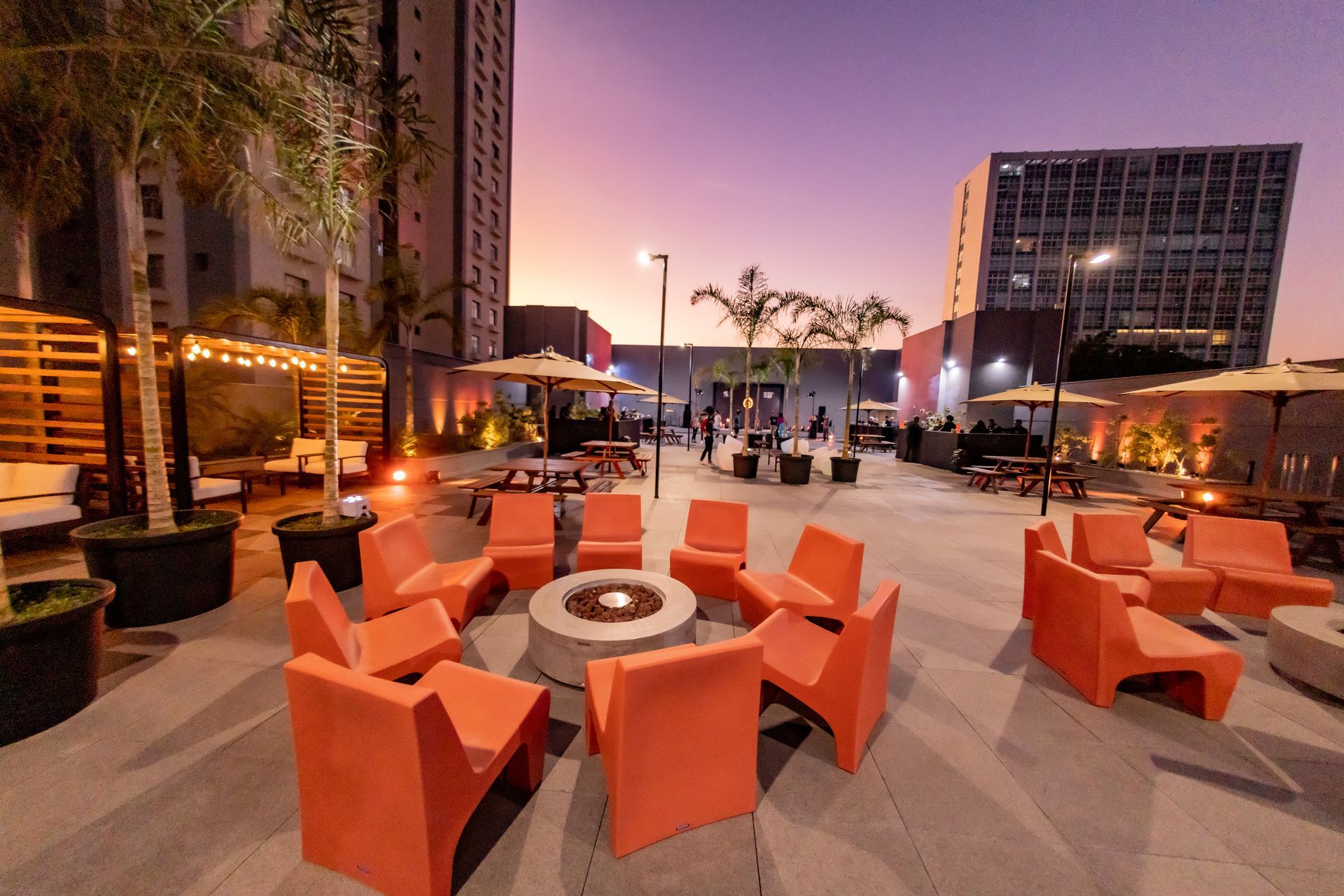 Un grupo de sillas de color naranja están colocadas alrededor de una fogata.