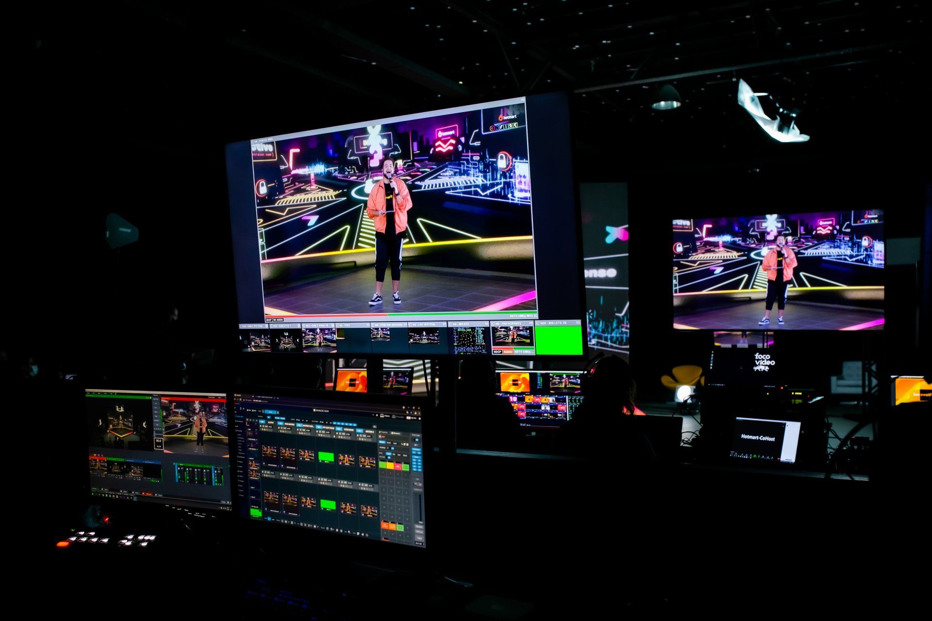 Um homem está em pé no palco em frente a uma tela grande.