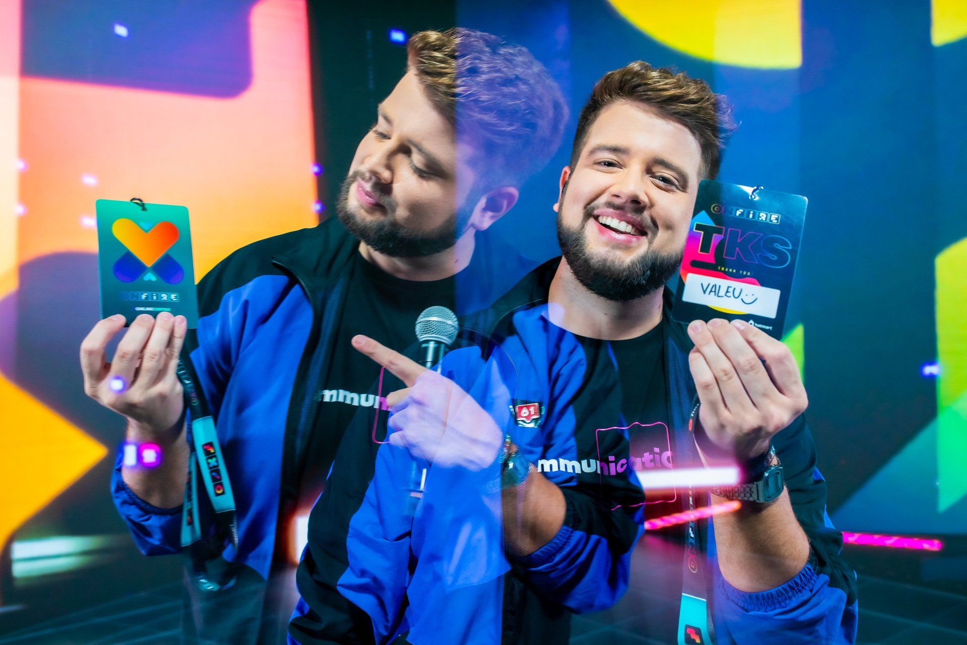 Dois homens estão de pé, um ao lado do outro, segurando um microfone e um cartão.