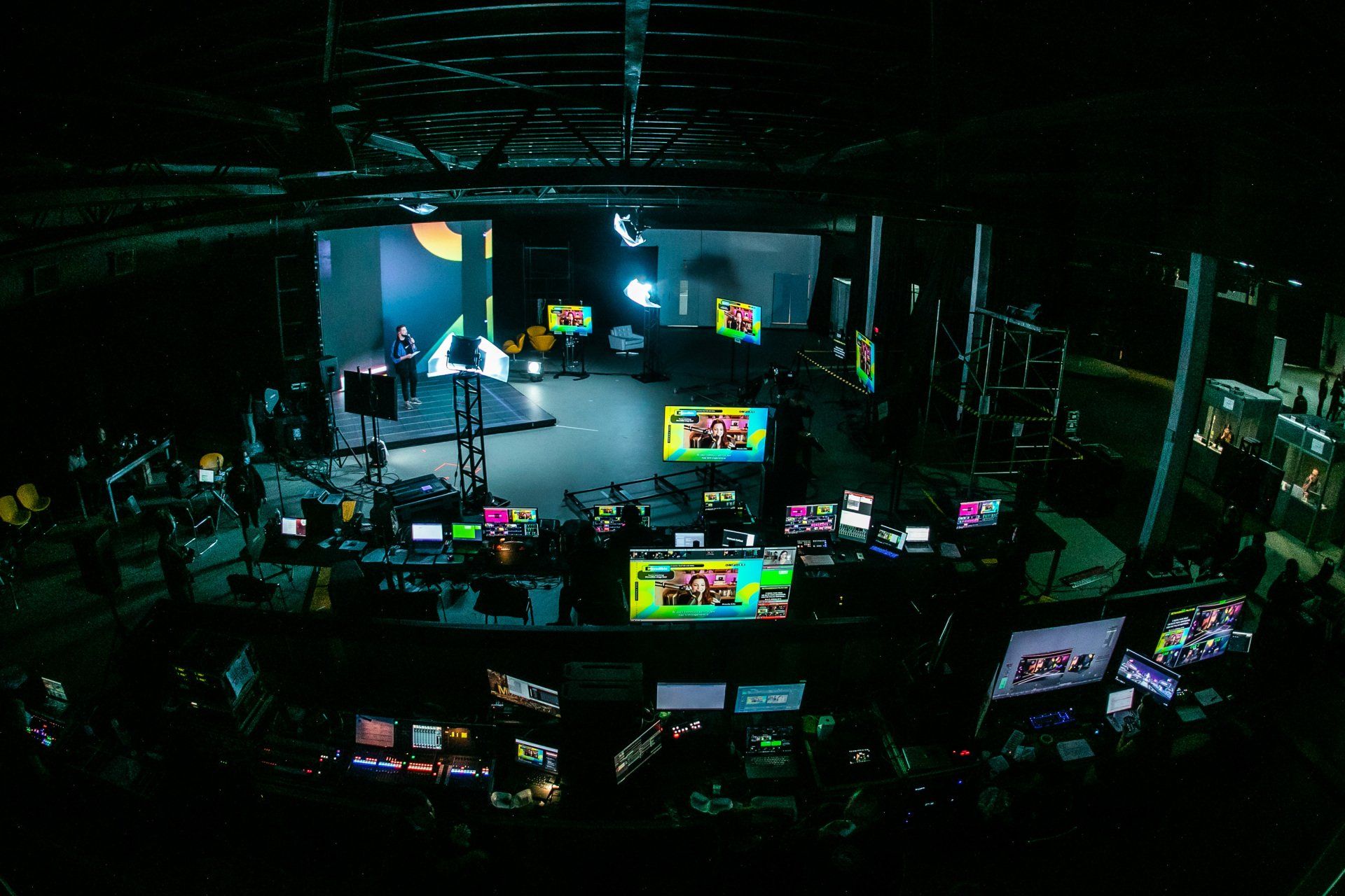 Uma sala escura com muitos monitores e uma tela que diz 'abc' nela