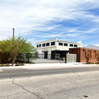 A large white building with a fence around it is next to a brick building.