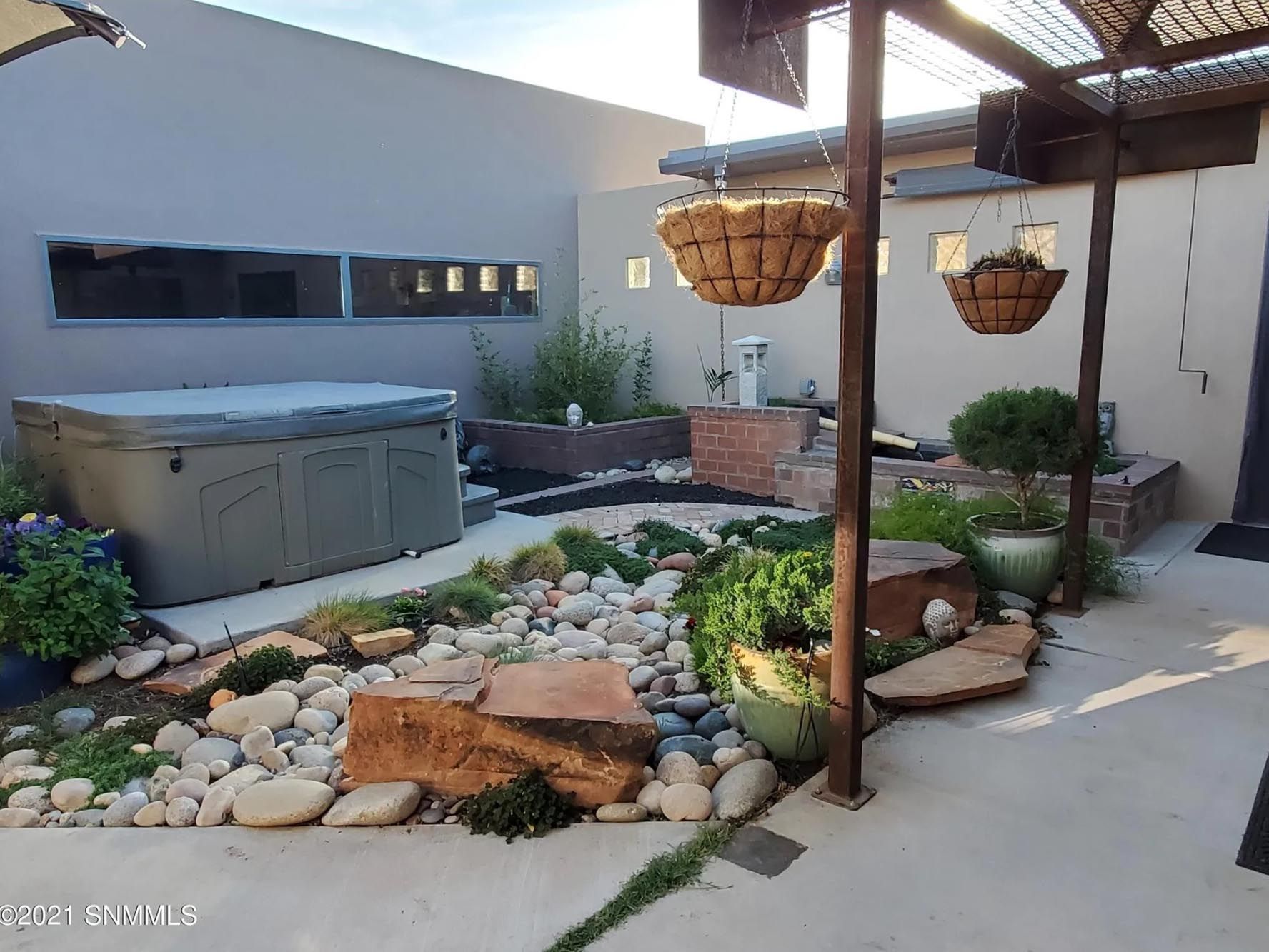 A backyard with a hot tub and hanging baskets