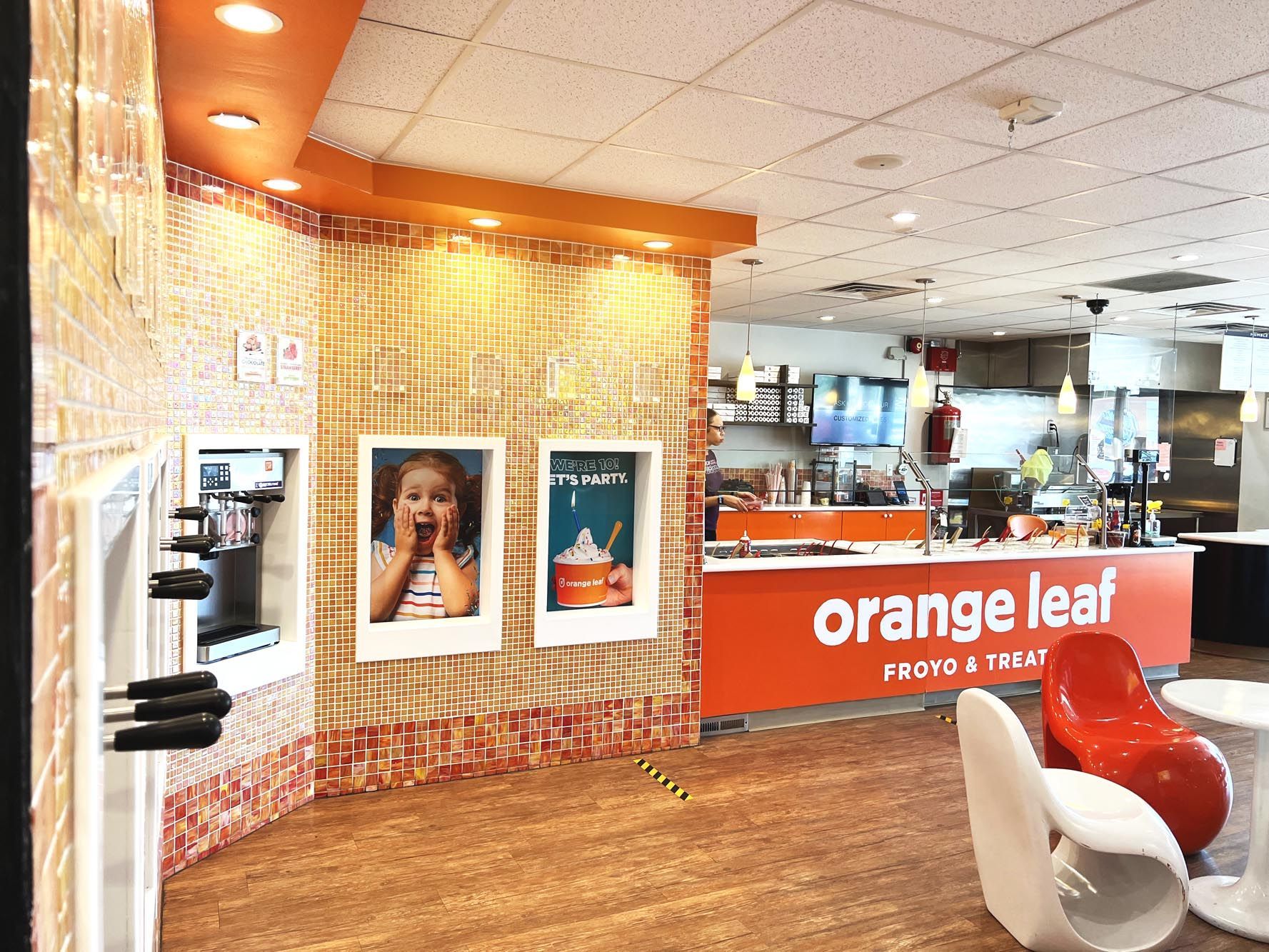 An orange leaf restaurant with red chairs and tables
