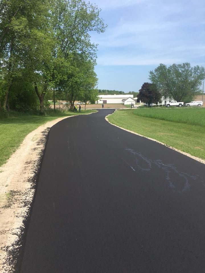 A black asphalt road going through a grassy field.