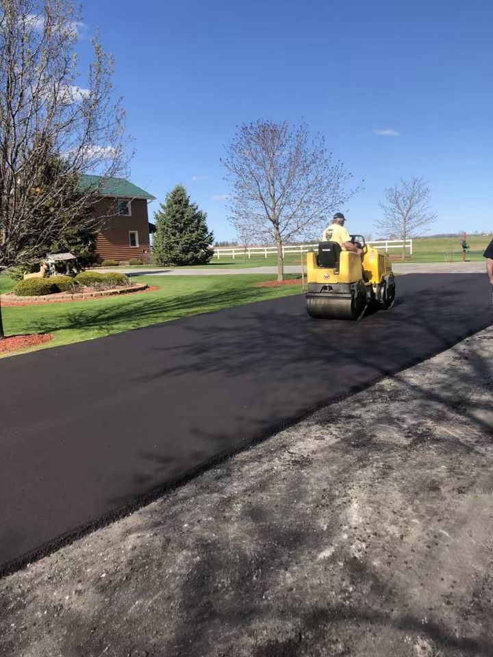 A man is driving a yellow roller down a driveway.