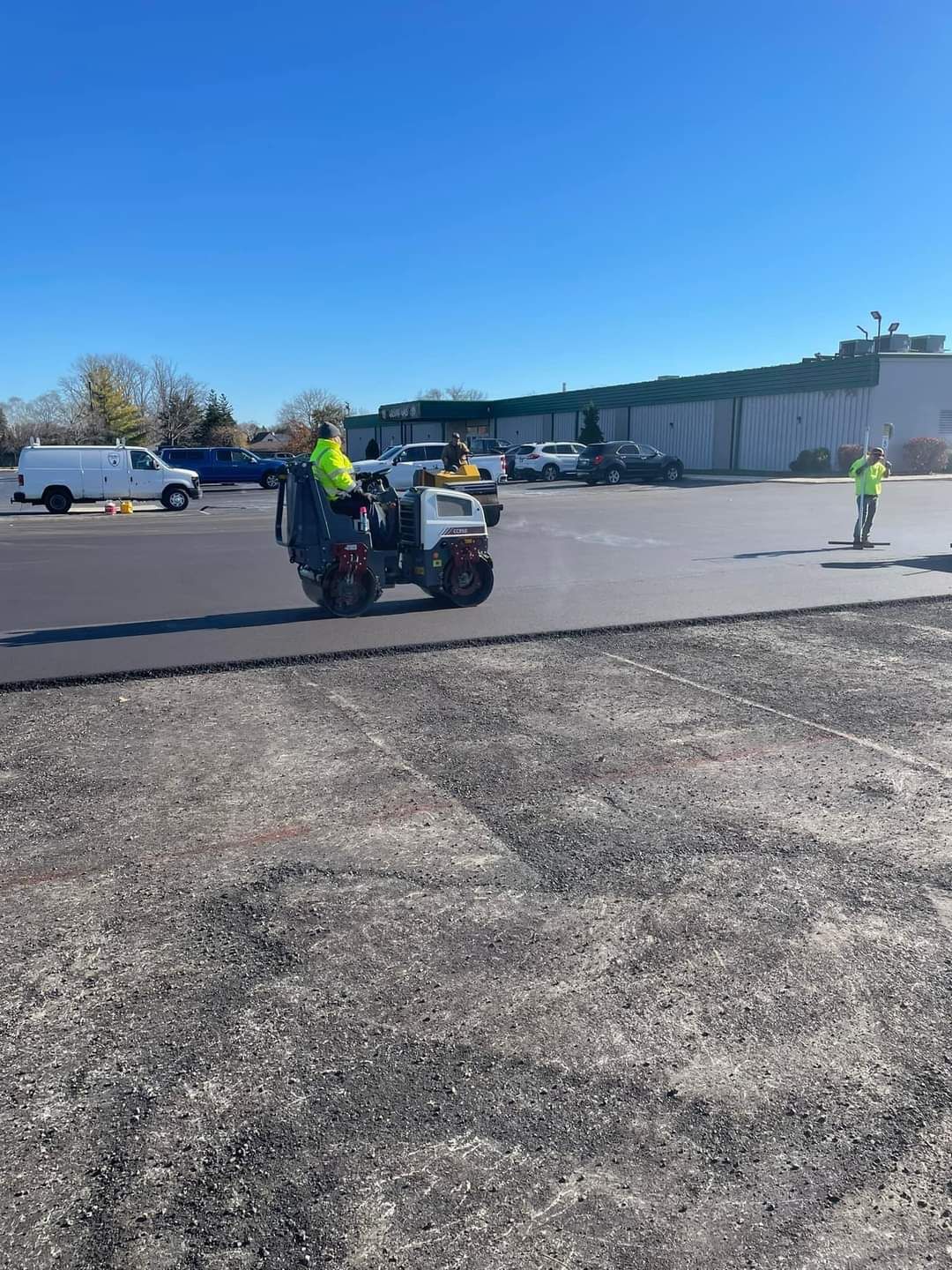 A group of people are working on a road in a parking lot.