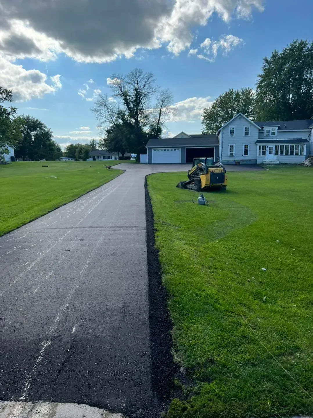 A lawn mower is parked on the side of a road next to a house.
