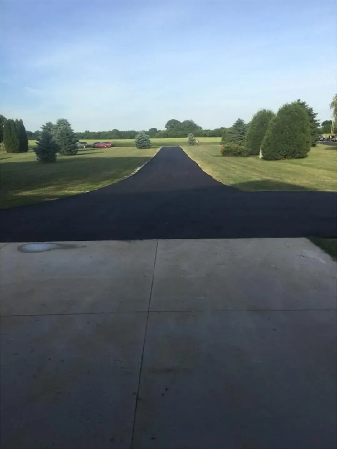 A view of a road going through a field from a driveway.