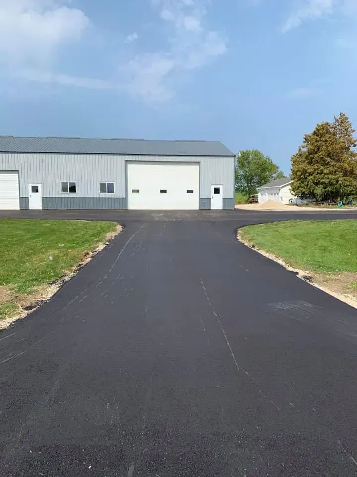 A driveway leading to a large building with a garage door.