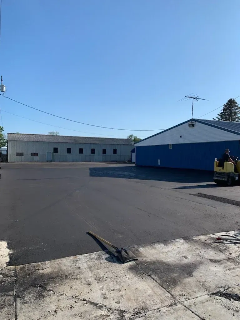 A large empty parking lot with a blue building in the background.