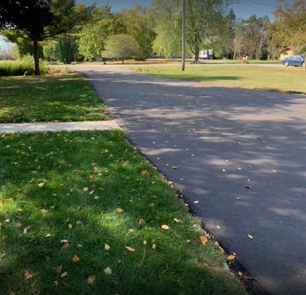 A road with grass on the side of it and trees on the side