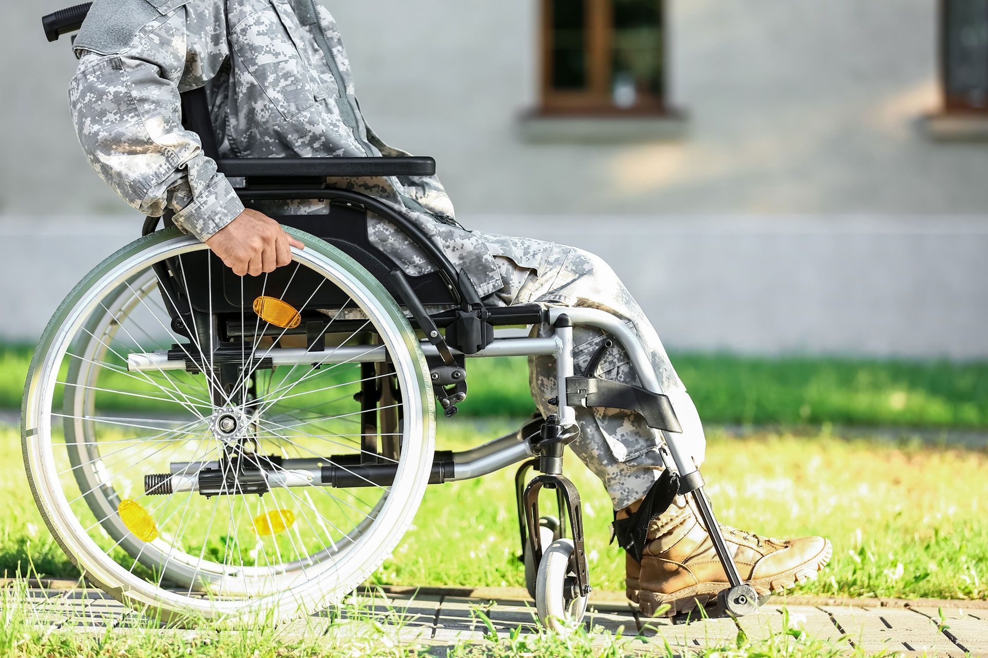 A soldier is sitting in a wheelchair on a sidewalk.