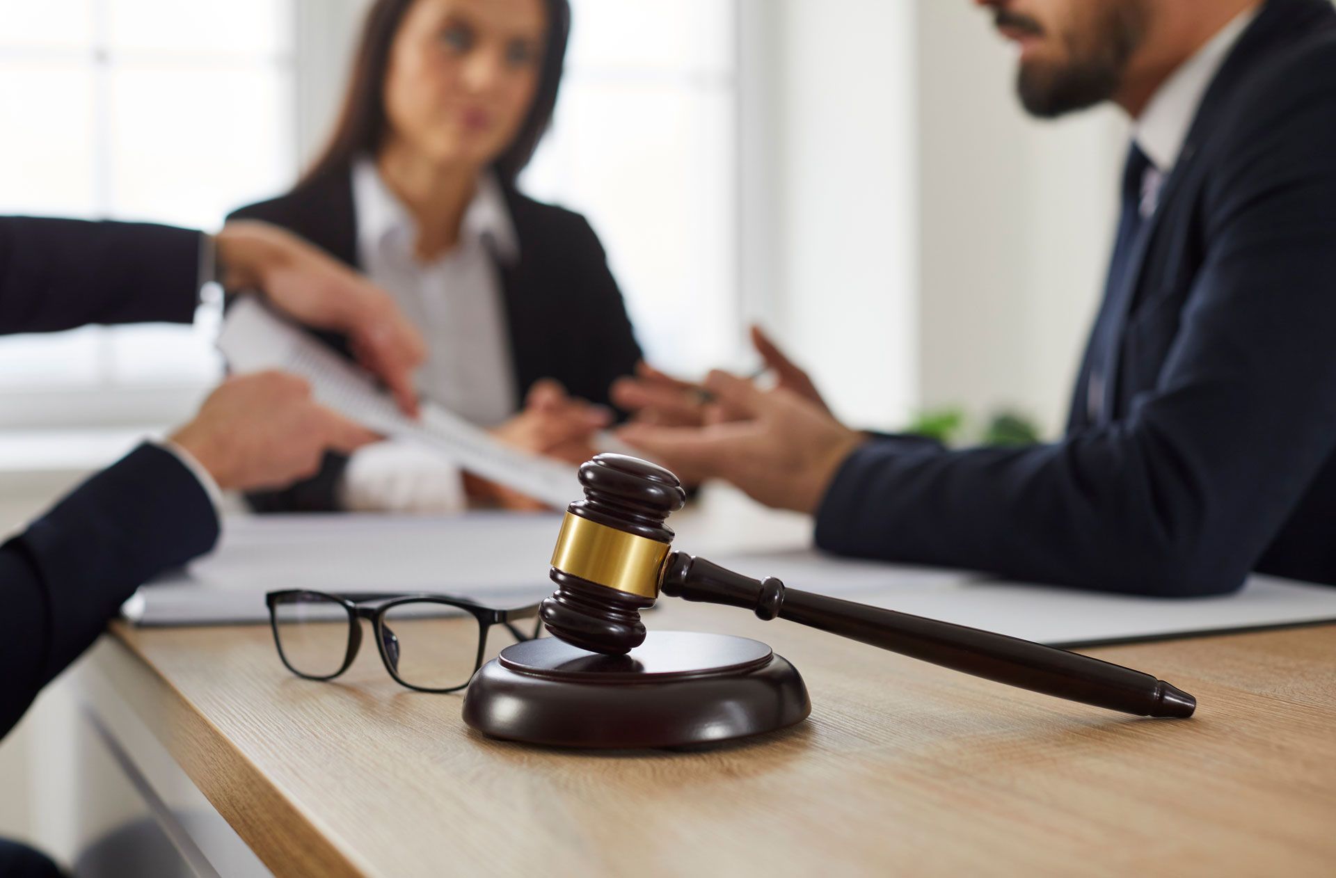 A judge 's gavel is sitting on a wooden table in front of a group of people.