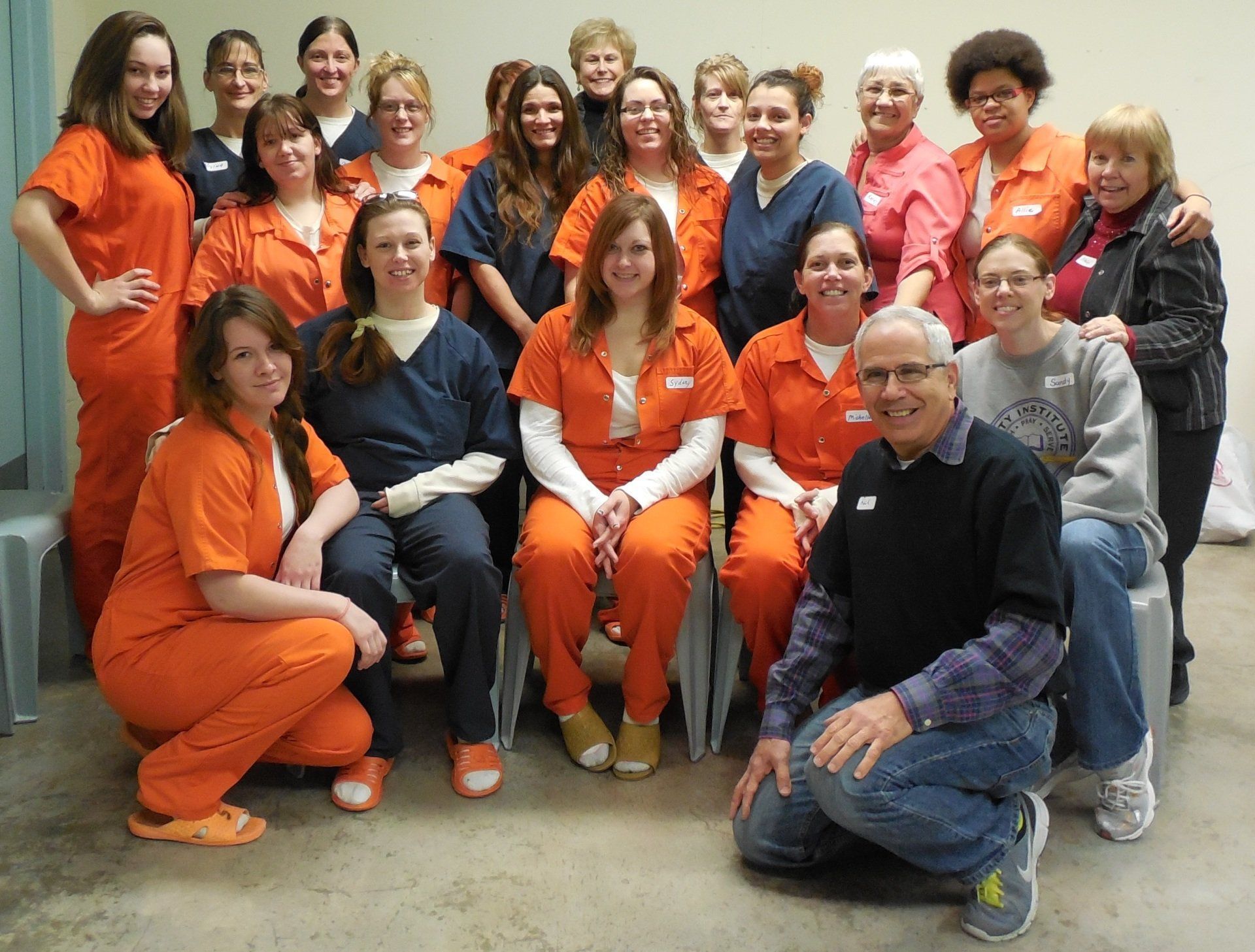A group of women in orange scrubs pose for a picture