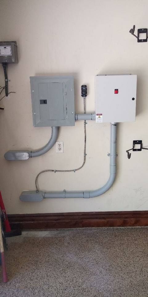 Electrical panel boxes and conduit on a wall in an interior space with a wood trim.