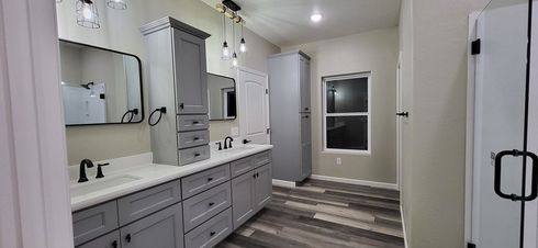 Bathroom with gray cabinets, a double vanity, and a window.