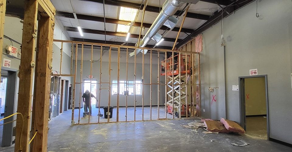 Interior of a building under construction, with wooden studs, insulation, and a person working.
