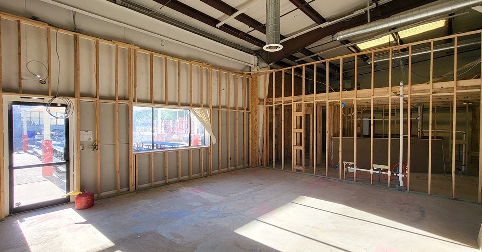 Interior view of a building under construction, featuring exposed wooden studs, a window, and a doorway.
