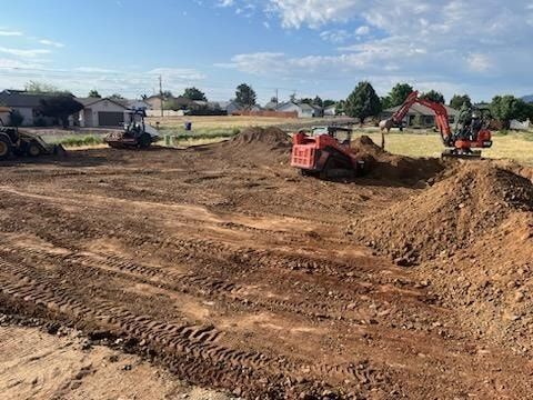 Construction site with heavy machinery, including an excavator and bulldozer, working on a dirt field.