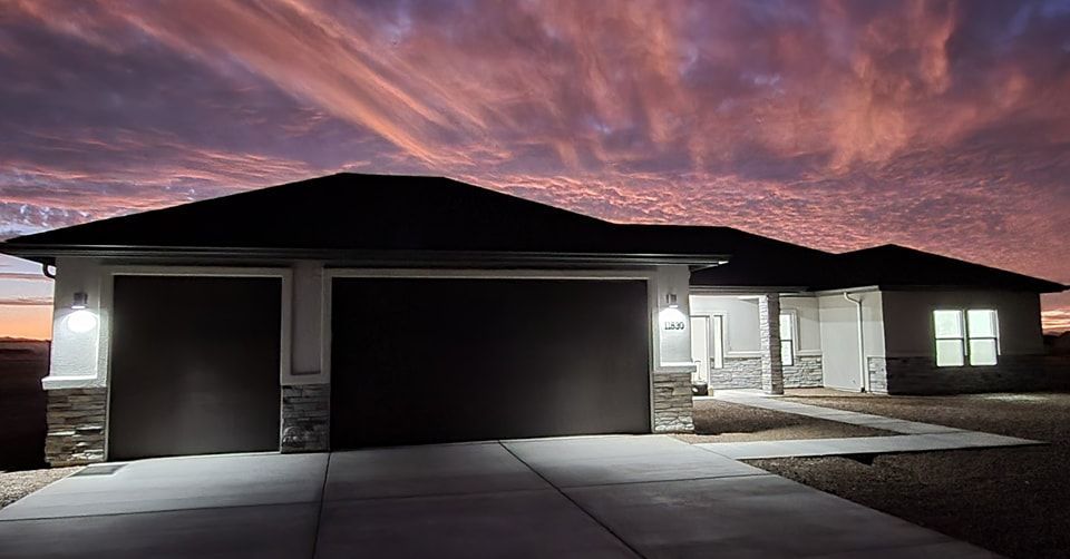 House at dusk with lit garage and a colorful sky.