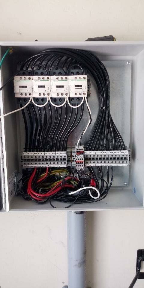 Electrical panel with multiple wires and components inside a metal box.