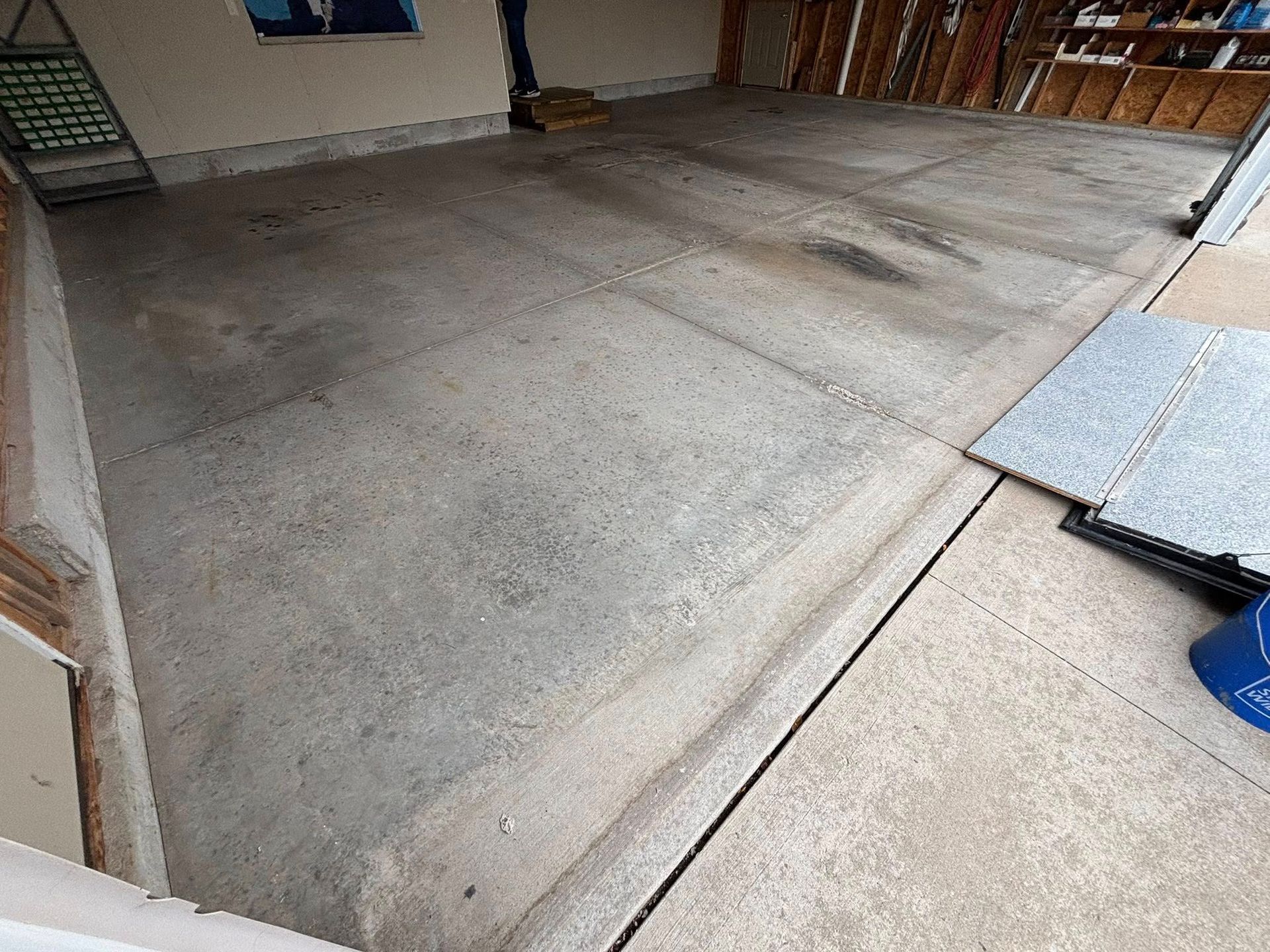 Concrete garage floor with dark stains, adjacent to a lighter-colored driveway.