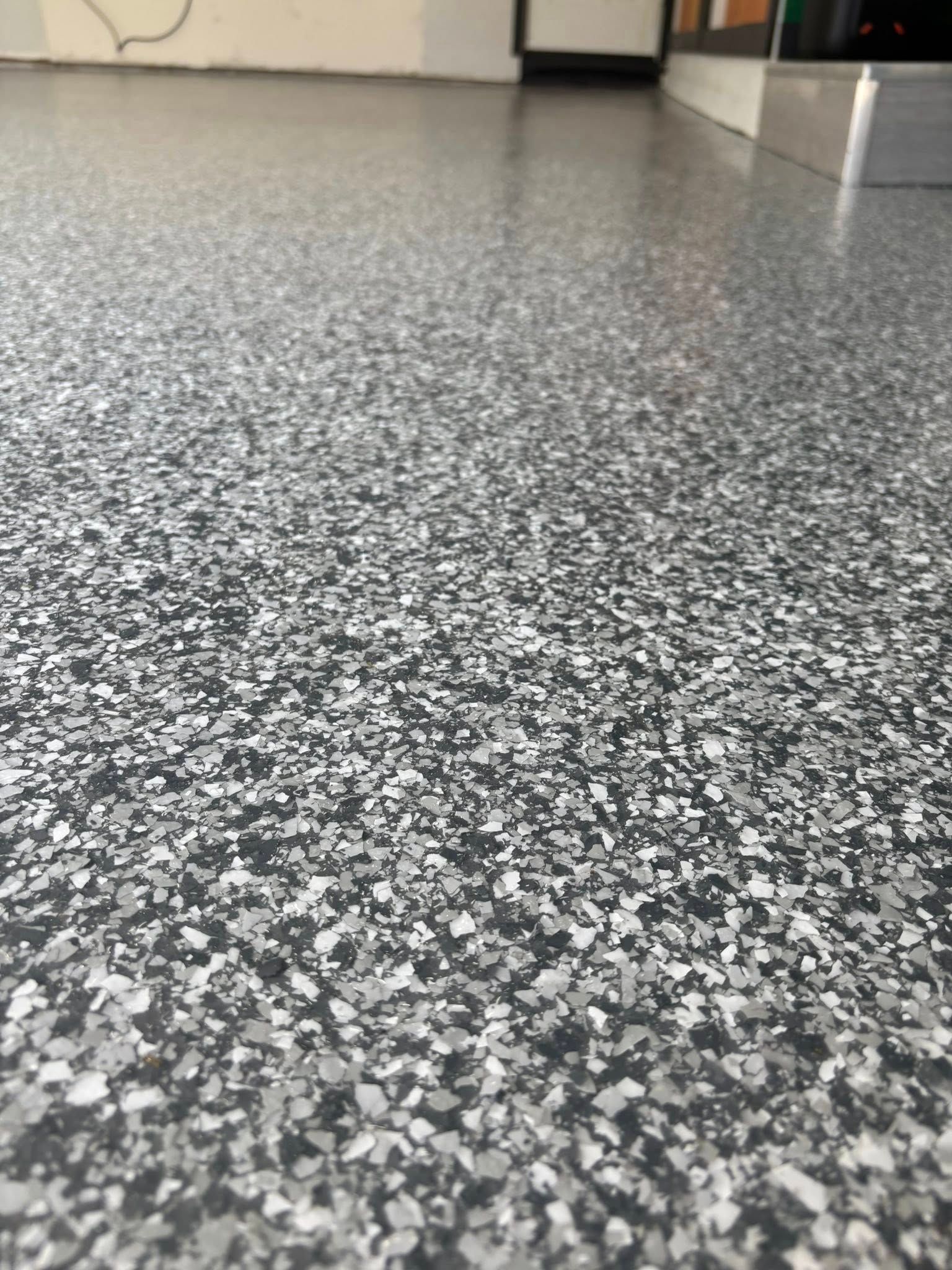 Gray and white speckled epoxy floor in a garage setting.