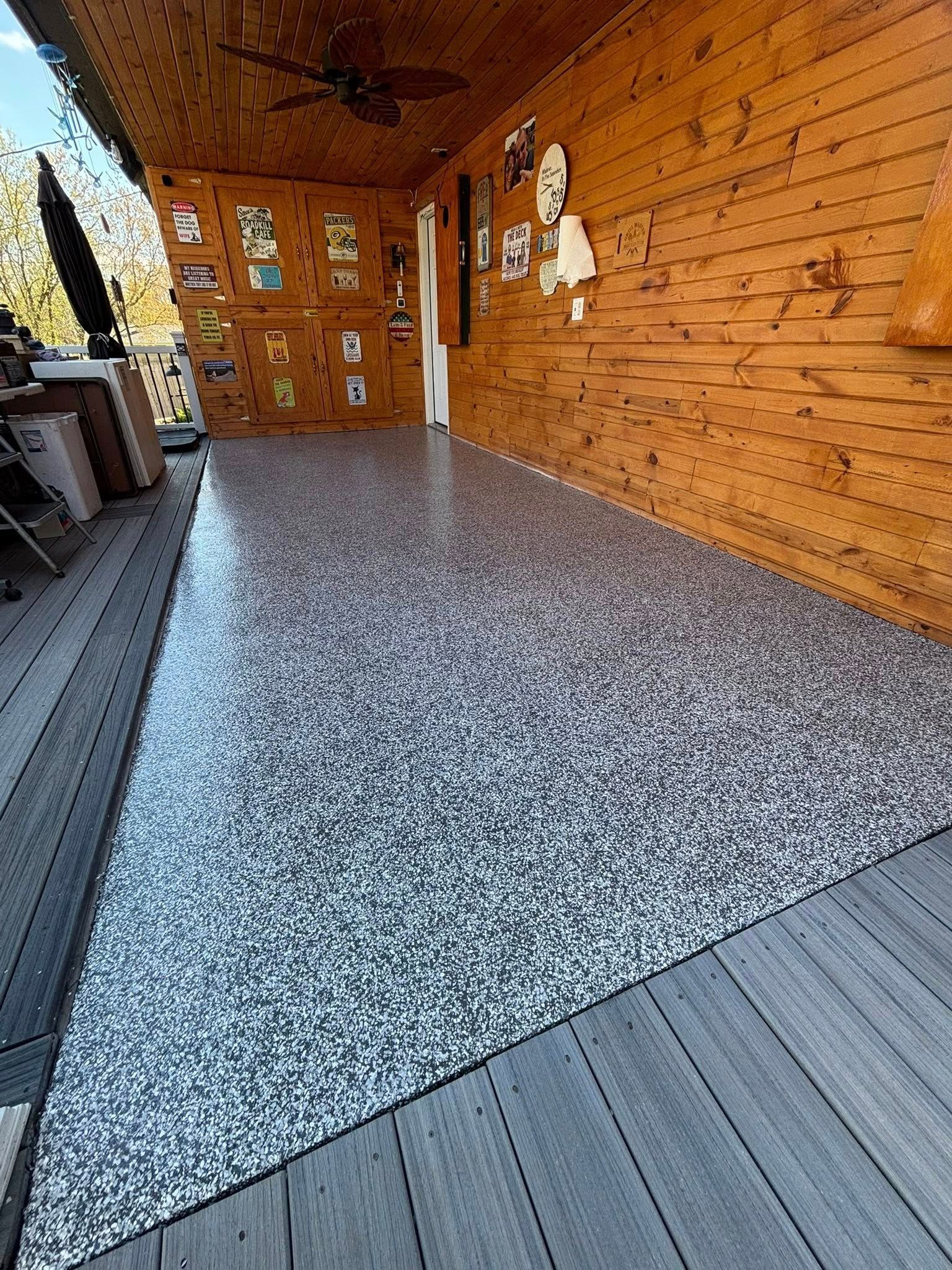 Porch with a speckled epoxy floor and wooden walls, lit from above.
