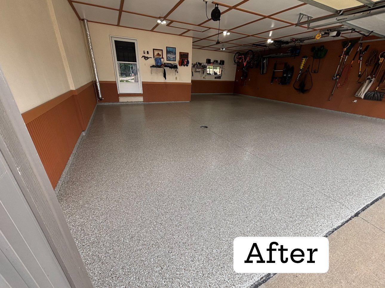 Garage with a newly coated, speckled gray floor. Interior walls are brown and beige.