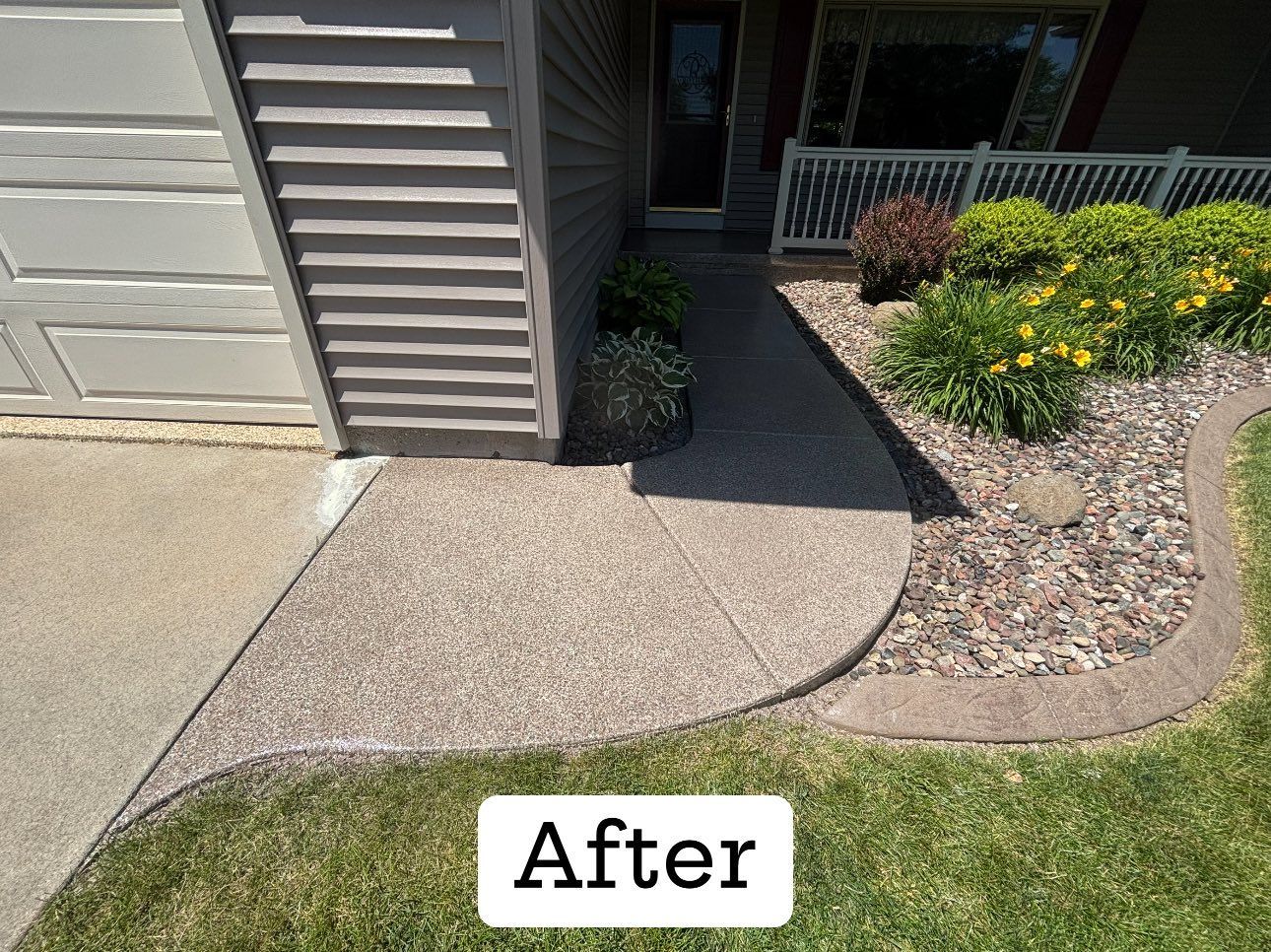 Newly-poured concrete walkway with textured finish, curved edge bordering a flower bed and lawn.