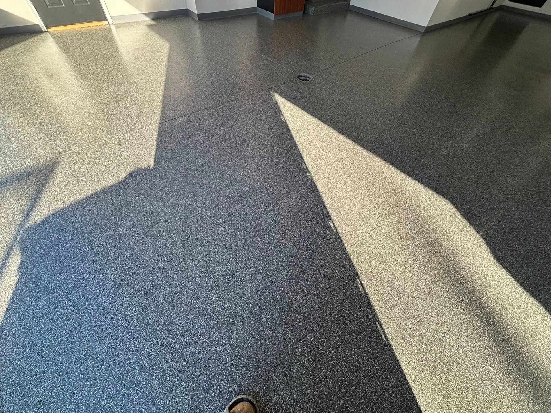 A speckled, dark gray floor with light and shadow patterns.