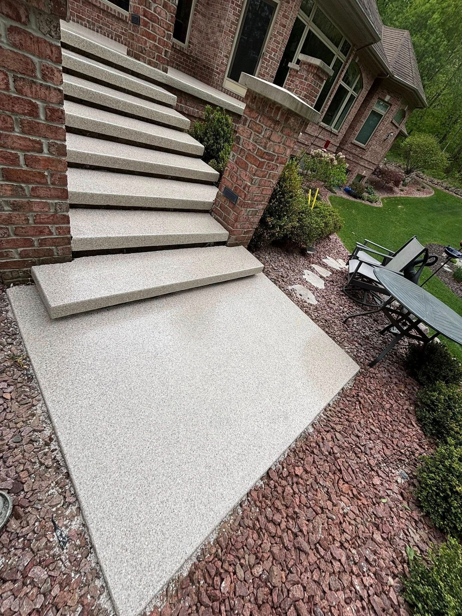 Concrete steps leading up to a brick house entrance with mulch landscaping.