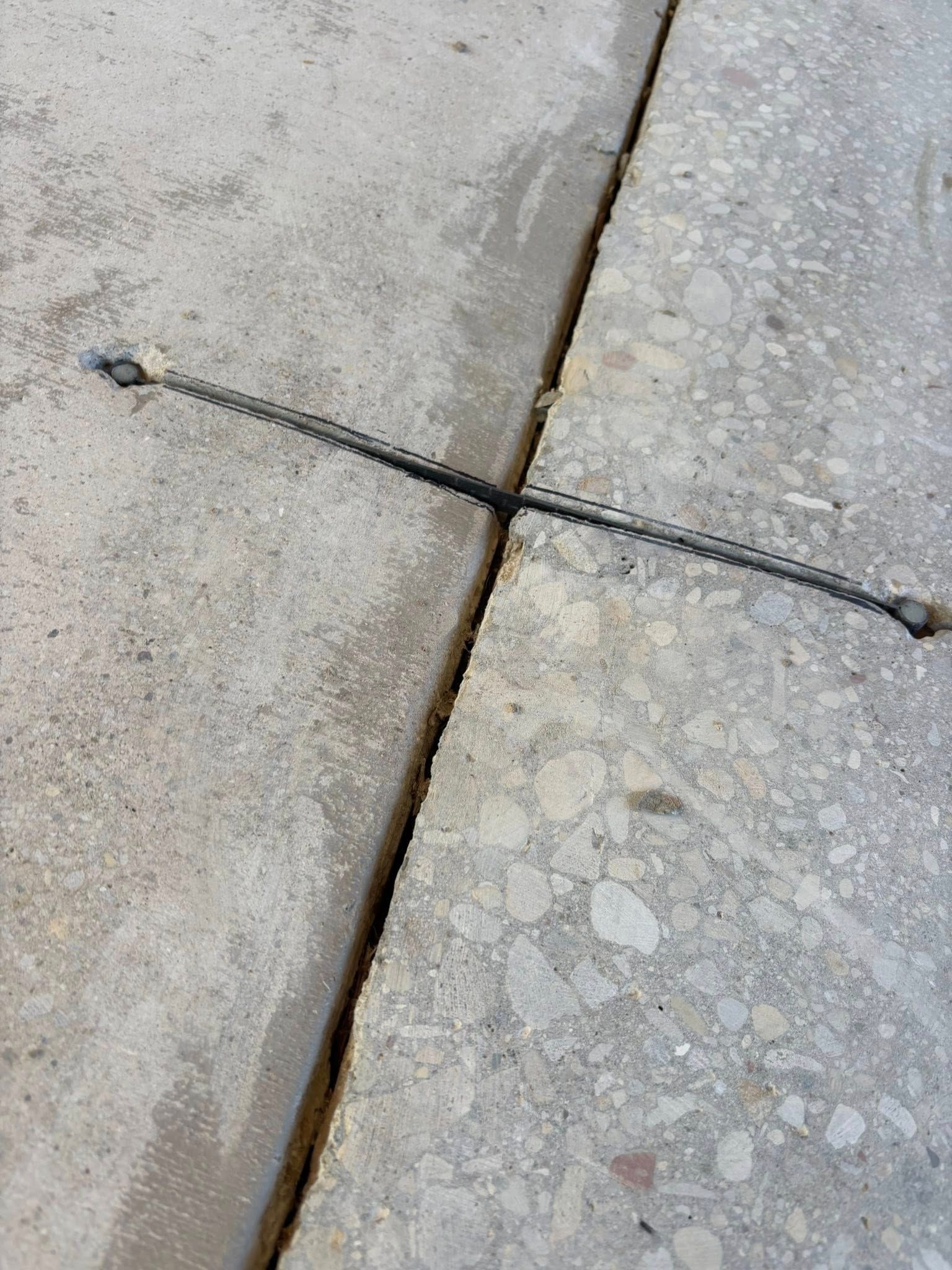 Concrete slabs with a metal chain spanning a joint.