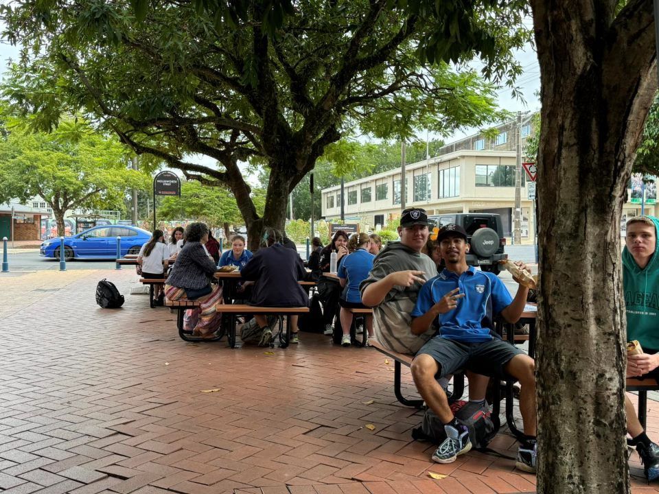 A Group of People Are Sitting at Picnic Tables Under a Tree — Lismore Pie Cart in Lismore, NSW