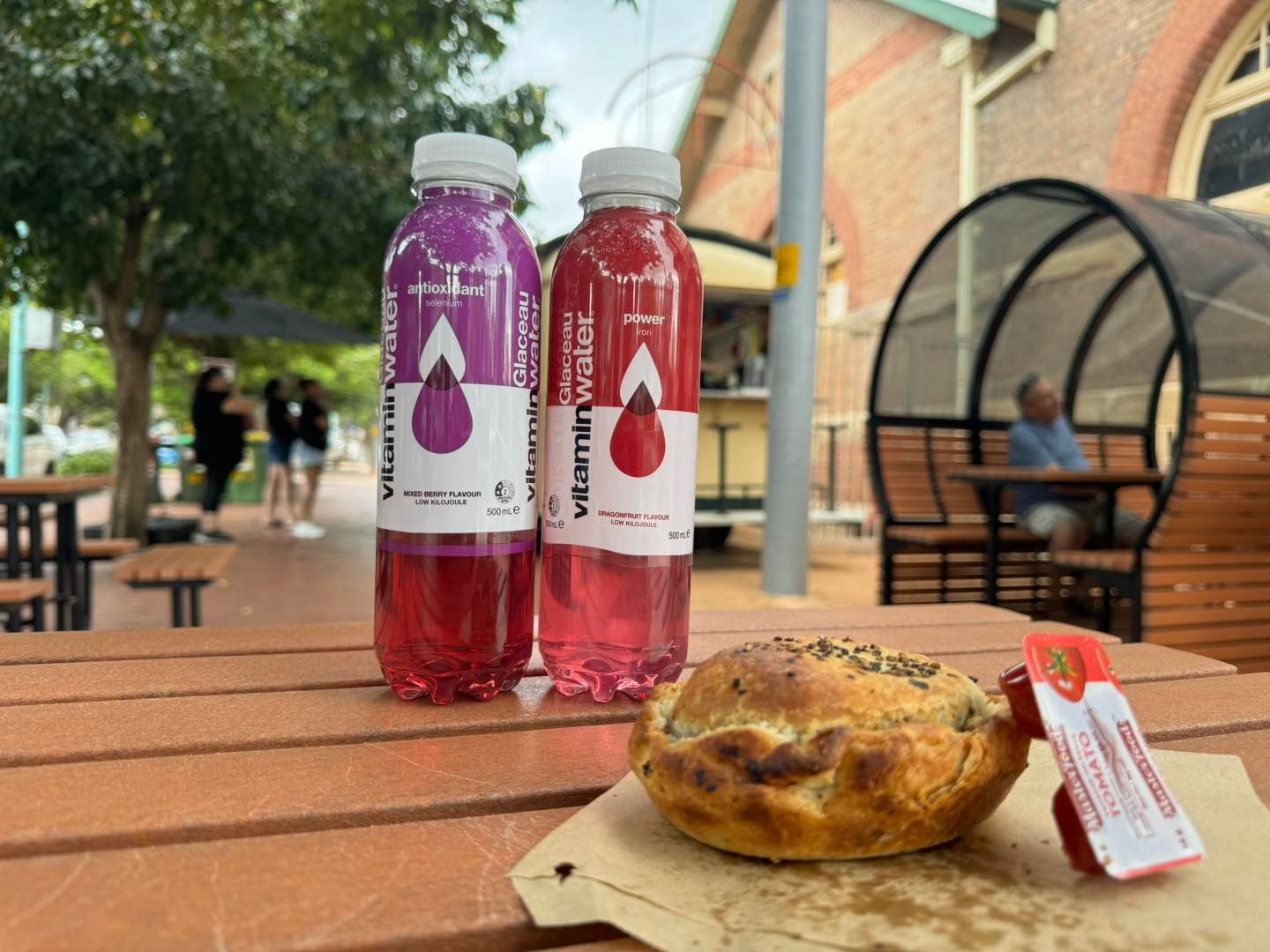 Two Bottles of Water and a Pie Are on a Wooden Table — Lismore Pie Cart in Lismore, NSW