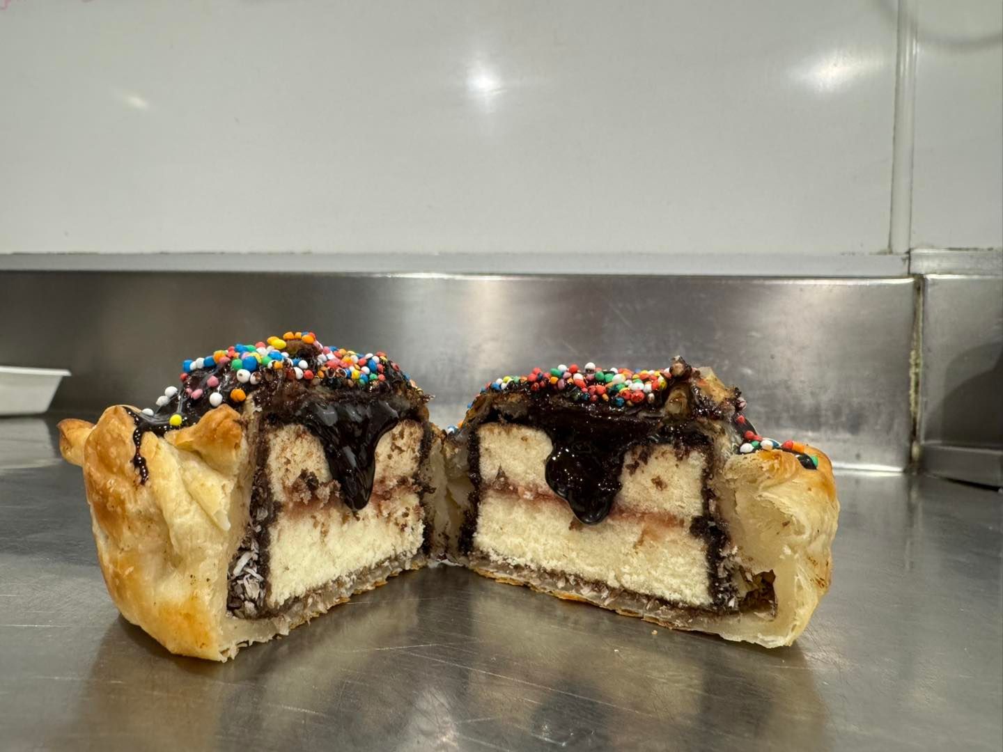 A Pie With Chocolate Icing and Sprinkles is Cut in Half on a Table — Lismore Pie Cart in Lismore, NSW