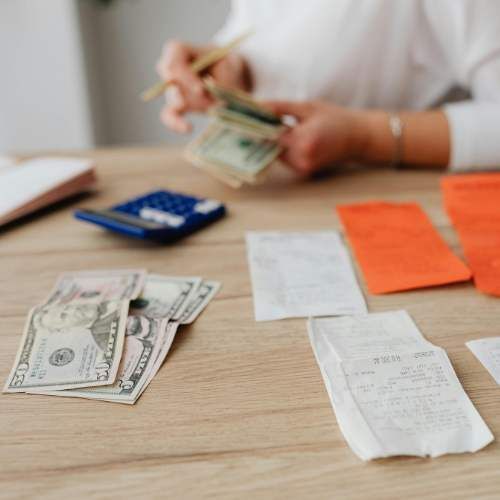 A woman is sitting at a table counting money and receipts.