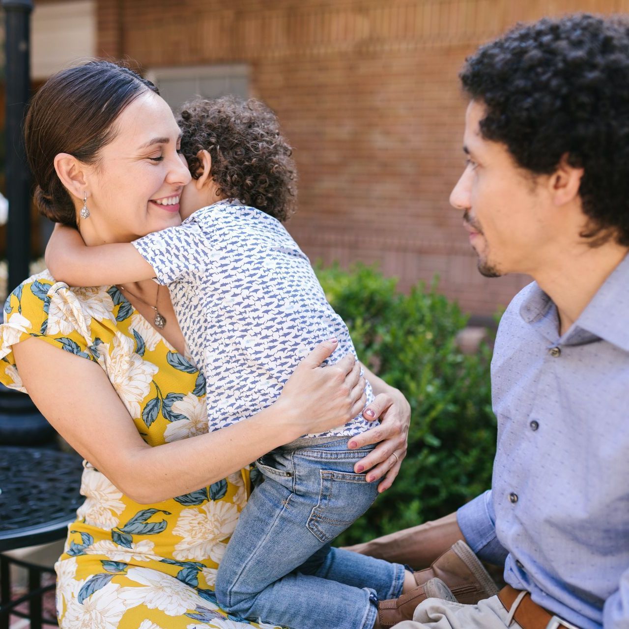 A woman is holding a child while a man looks on.