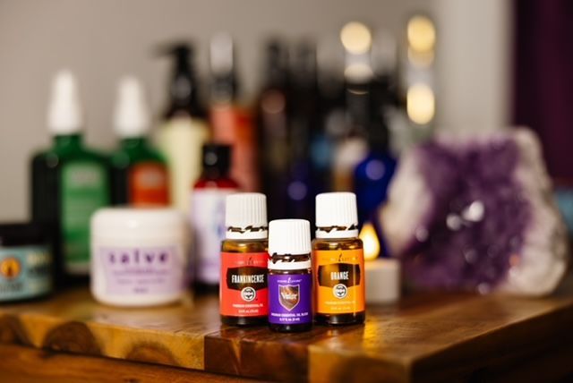 Brown dropper bottle with a drop of liquid falling, background blurred green leaves.