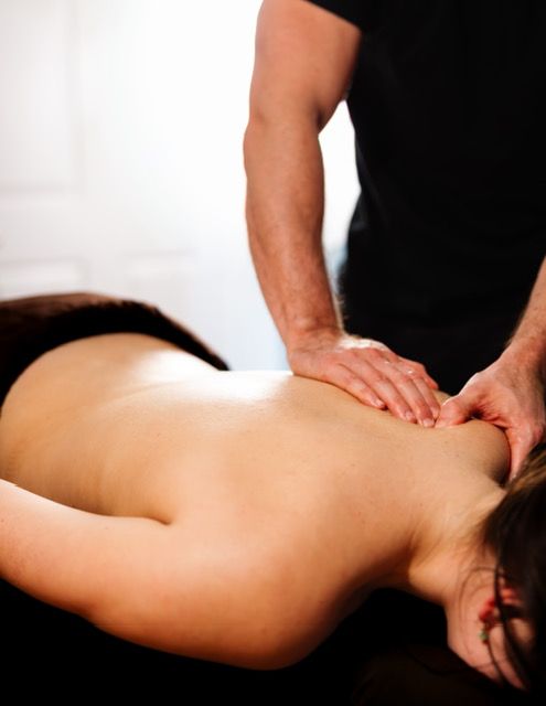 Woman receiving facial massage at a spa; hands on face, eyes closed.