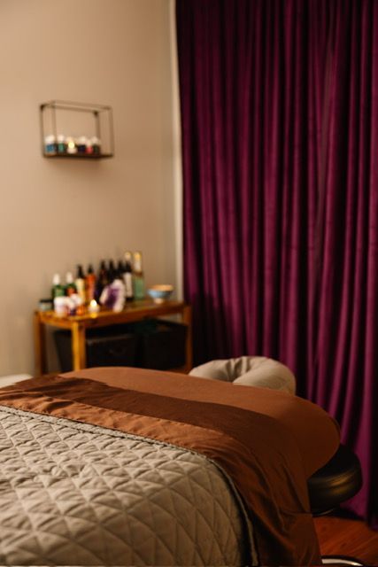 Massage therapist giving a back massage in a room with a table, curtains, and equipment.