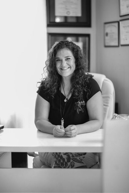 Woman seated at a desk, smiling, in an office setting.