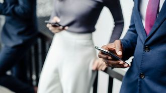 a man in a suit and tie is holding a cell phone .