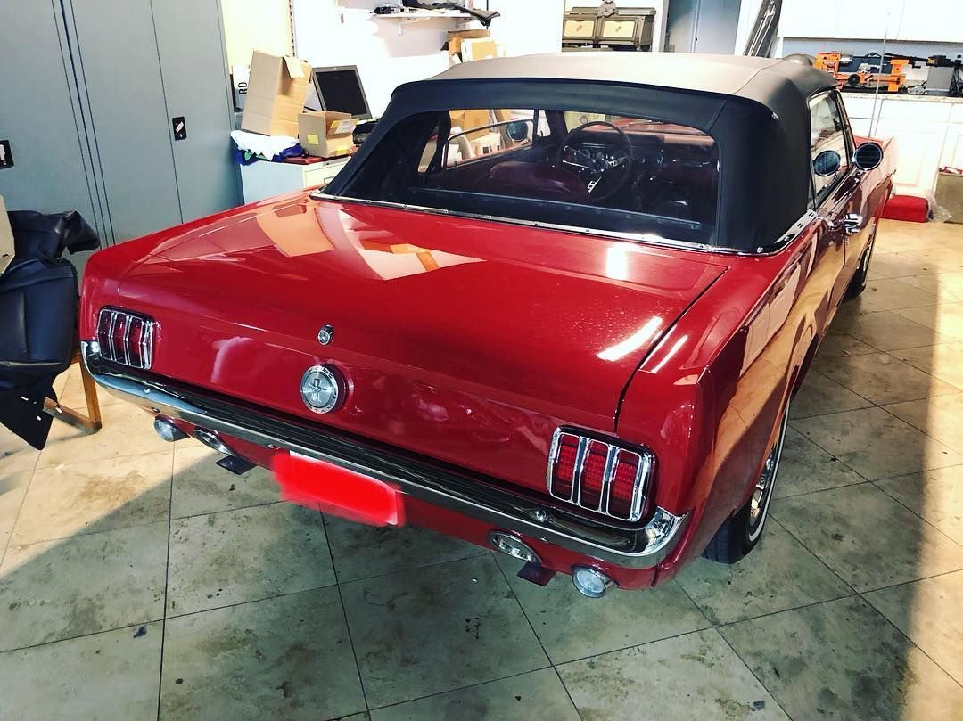 A red mustang convertible is parked in a garage.