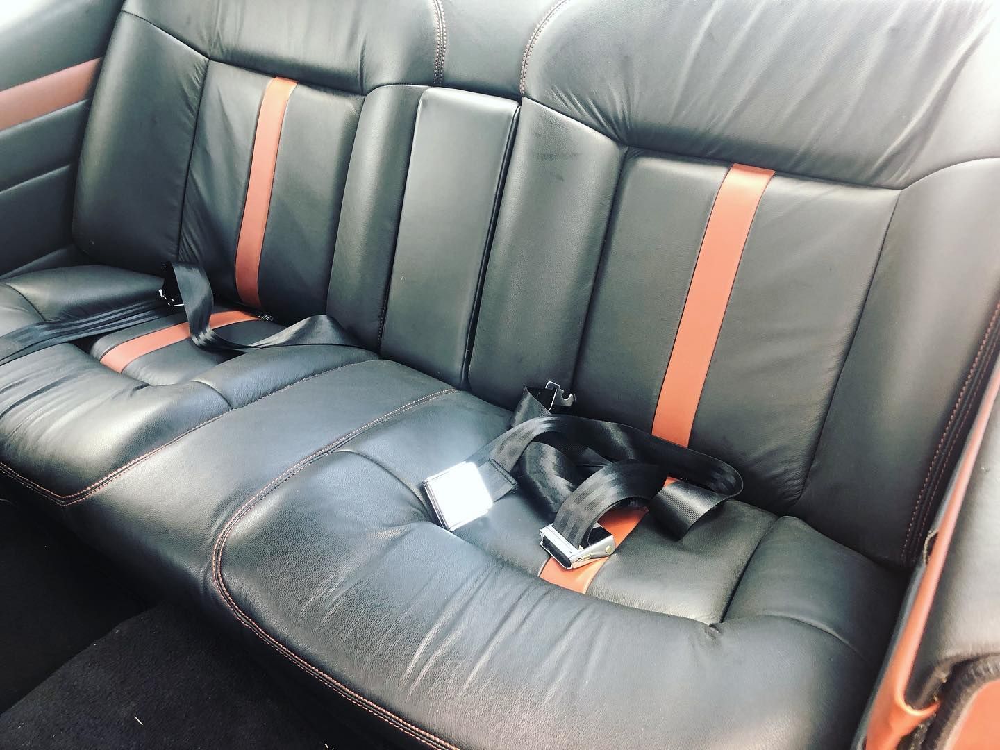 The back seat of a car with seat belts on it