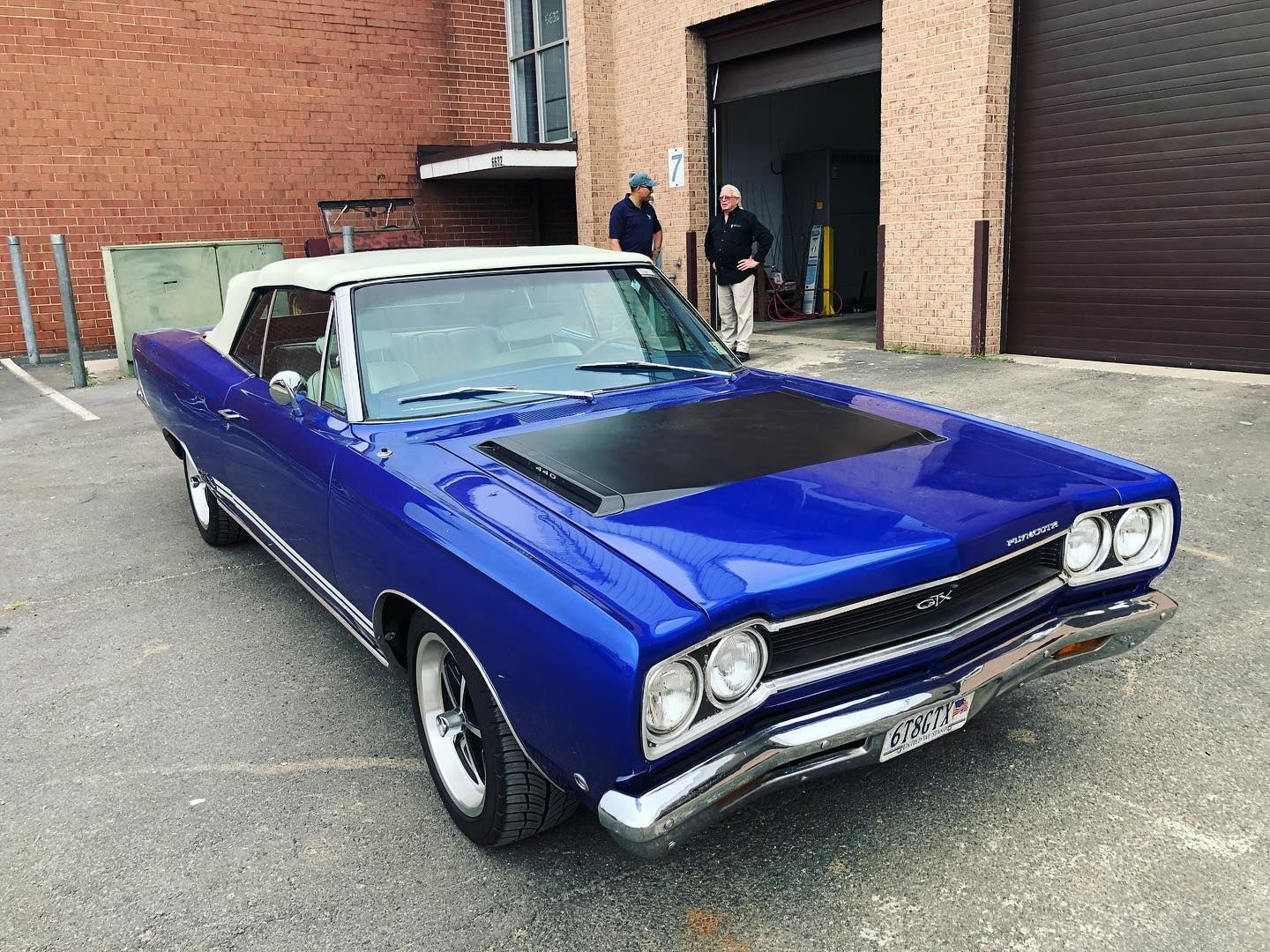 A blue car is parked in front of a brick building.