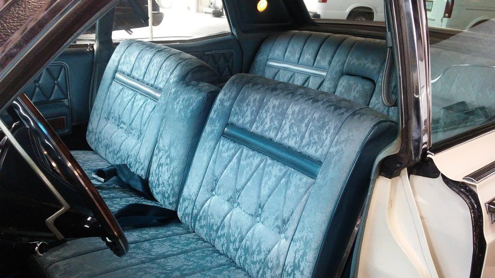 The inside of a car with blue seats and a steering wheel.