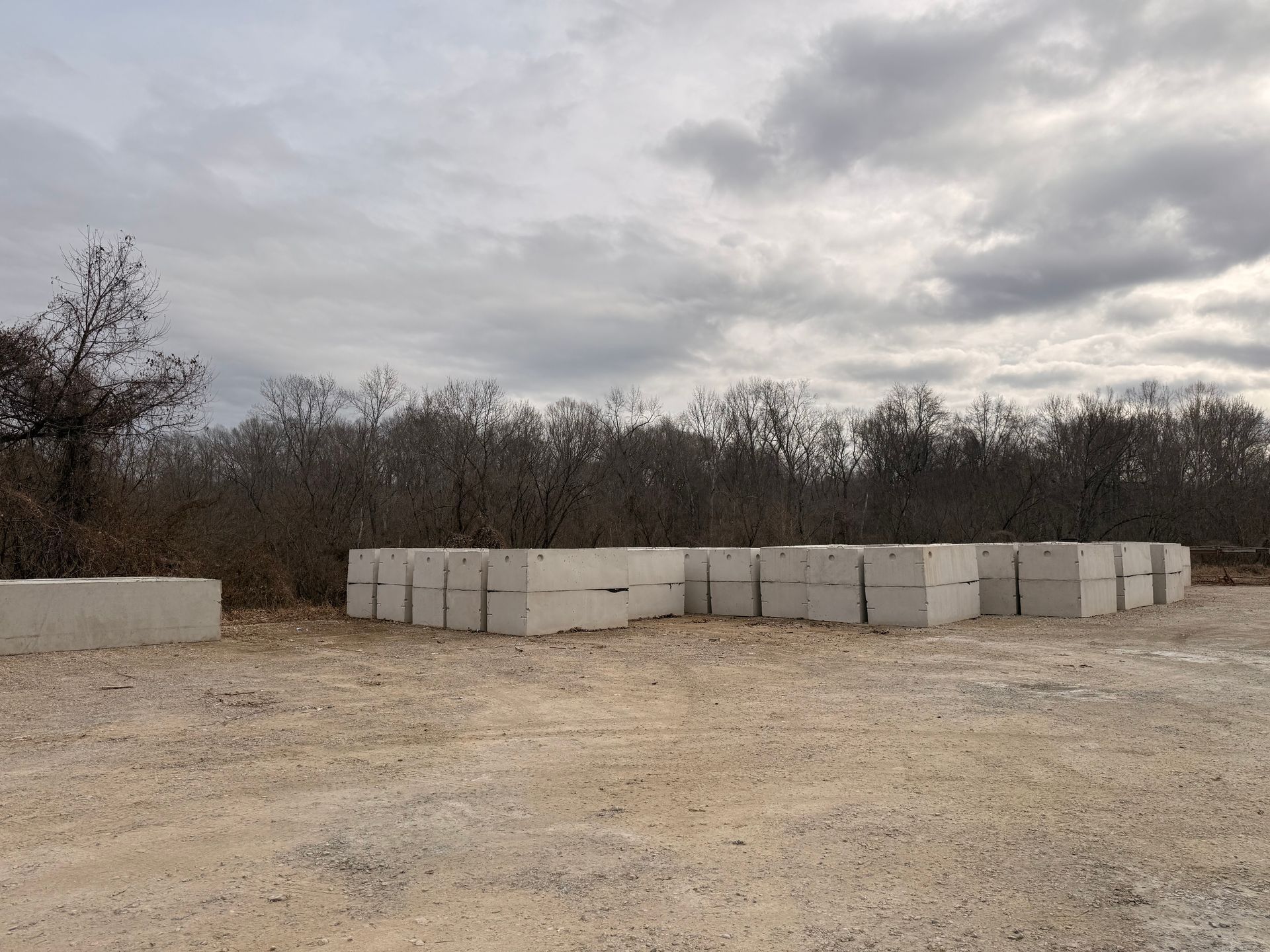 Person in red gloves holding blue hose, feeding into open concrete septic tank.